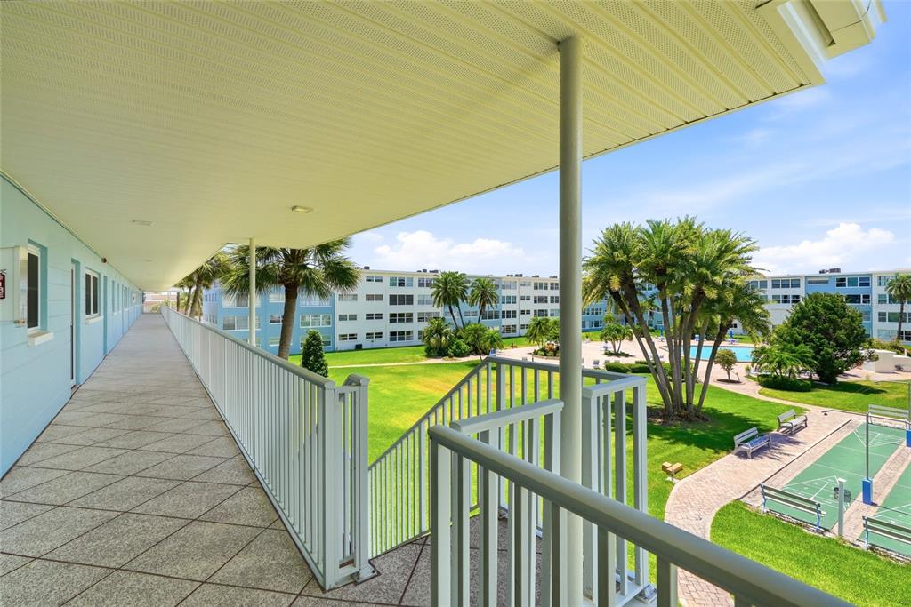 An outdoor apartment building walkway with blue walls, tiled floors, and labeled unit entrances — 6201 2ND STREET E UNIT 106, ST PETE BEACH, FL
