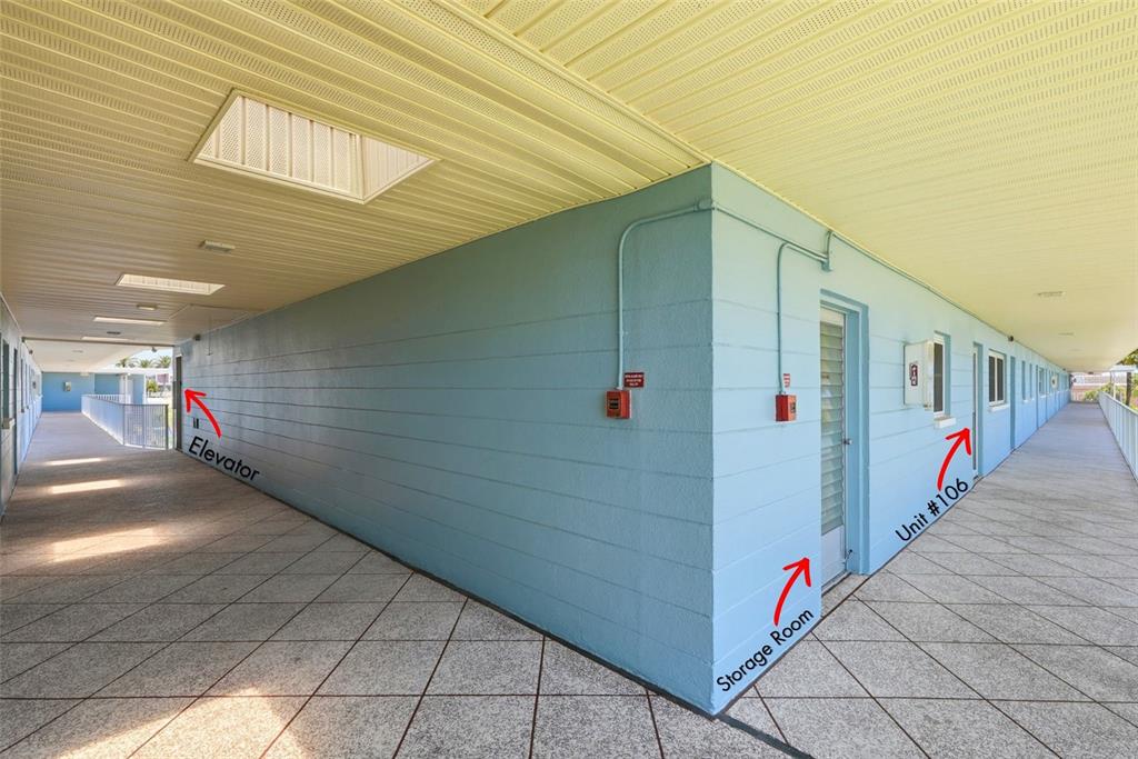 A light blue exterior walkway with a tiled floor and a white door — 6201 2ND STREET E UNIT 106, ST PETE BEACH, FL