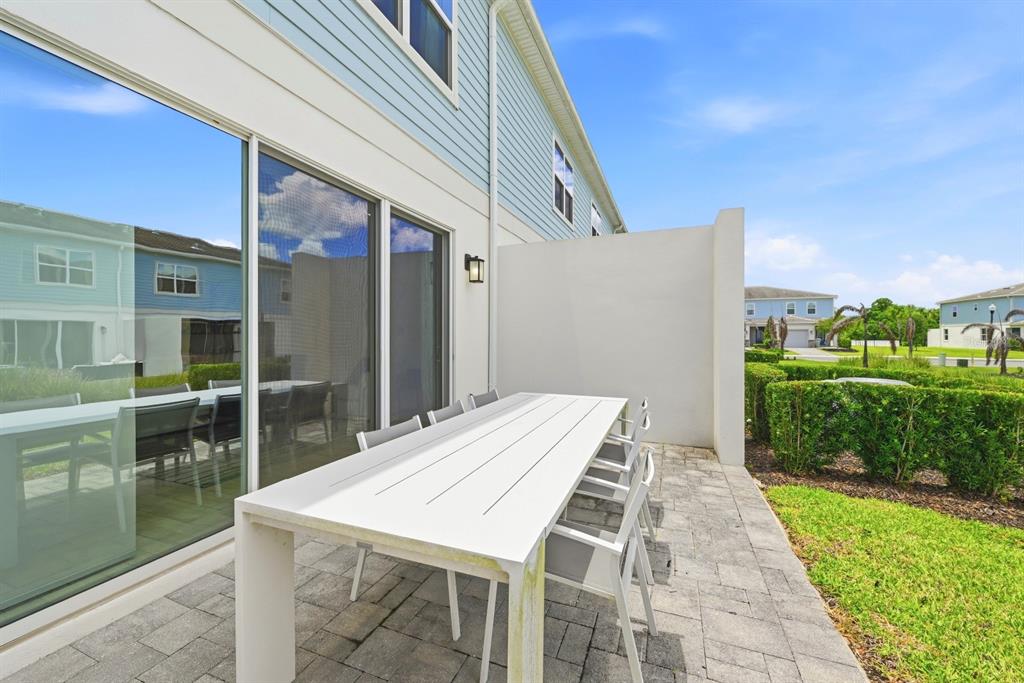 A white outdoor dining table sits on a paved patio beside a blue townhouse exterior — 7909 DRAW STREET, REUNION, FL
