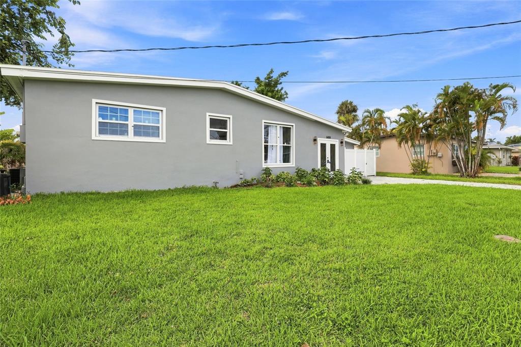 A gray, single-story house with a sloped roof sits behind a large, green grassy lawn — 6488 ANGLE PLACE, NORTH PORT, FL