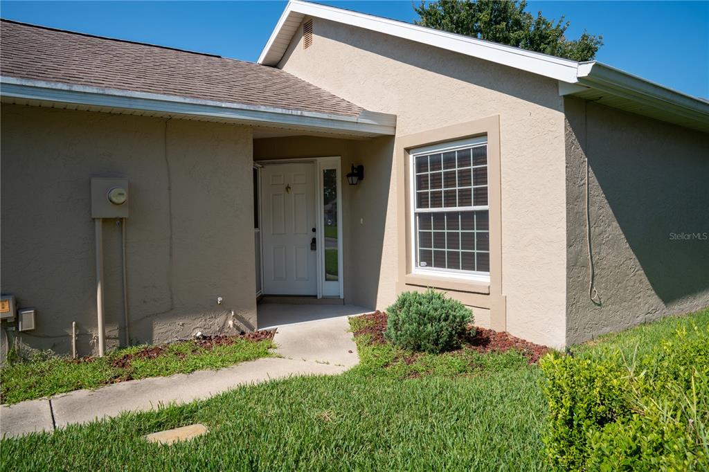 The exterior of a tan stucco house features a front entrance and a single window — 1913 NW 50TH CIRCLE, OCALA, FL