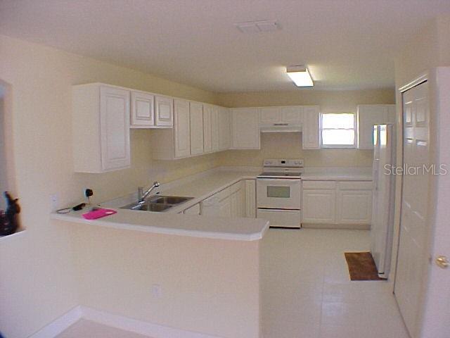 A kitchen with white cabinets, white appliances, and a peninsula counter — 960 CHASE COURT, WINTER GARDEN, FL