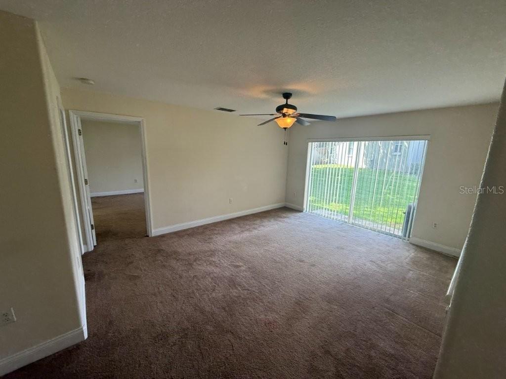An empty room with brown carpet, a ceiling fan, and sliding glass doors to outside — 960 CHASE COURT, WINTER GARDEN, FL