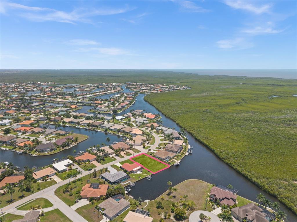 An aerial view shows a vacant waterfront lot outlined in pink within a residential neighborhood — 3324 TRIPOLI BOULEVARD, PUNTA GORDA, FL