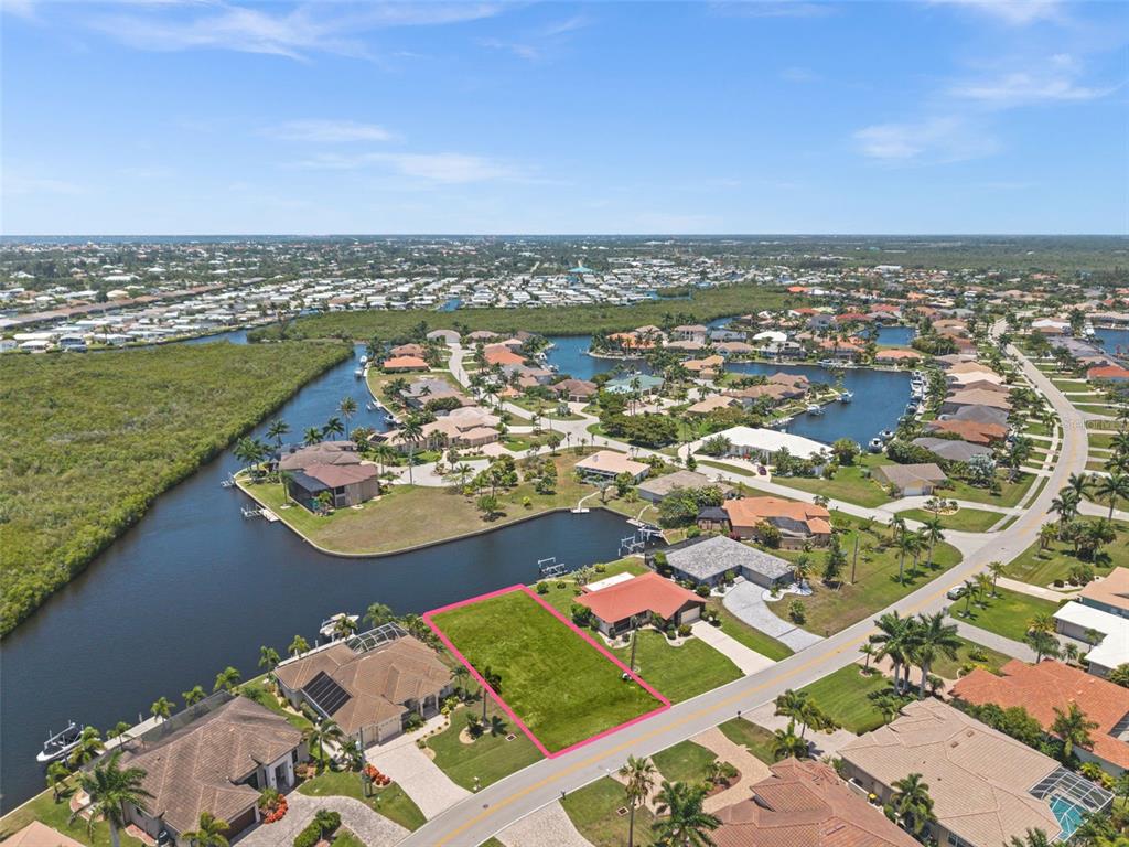 An aerial view shows a vacant, rectangular waterfront lot outlined in pink — 3324 TRIPOLI BOULEVARD, PUNTA GORDA, FL