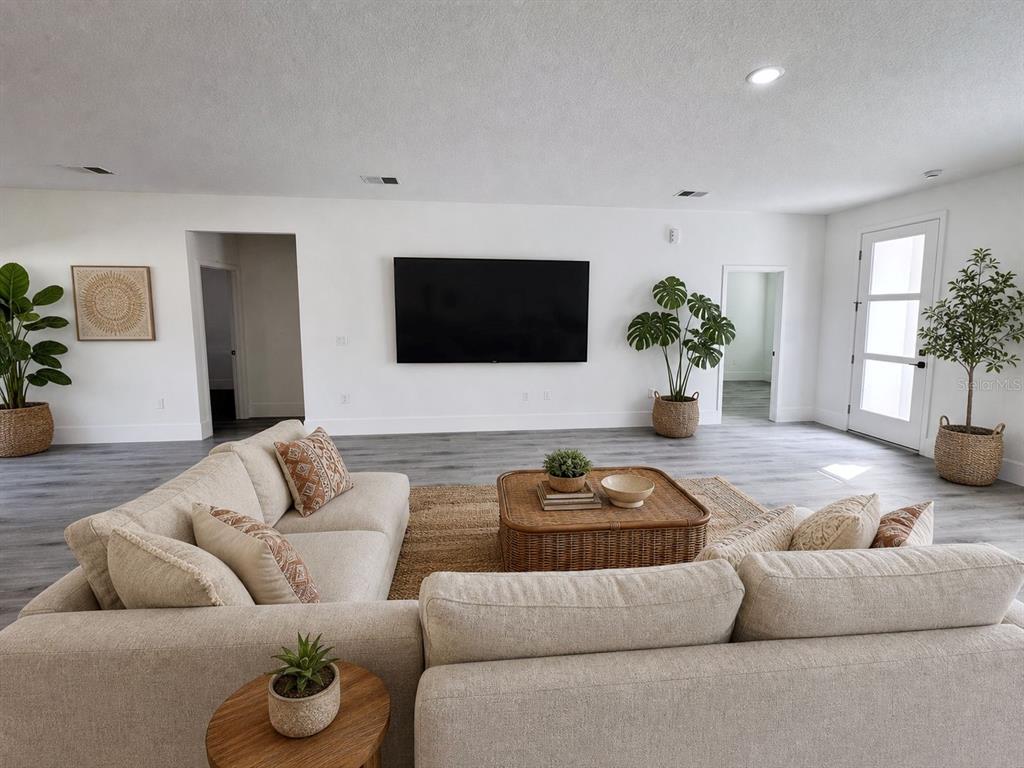 A living room features a beige sectional sofa, a rattan coffee table, and a wall-mounted television — 3741 W FOREST DRIVE W, DUNNELLON, FL