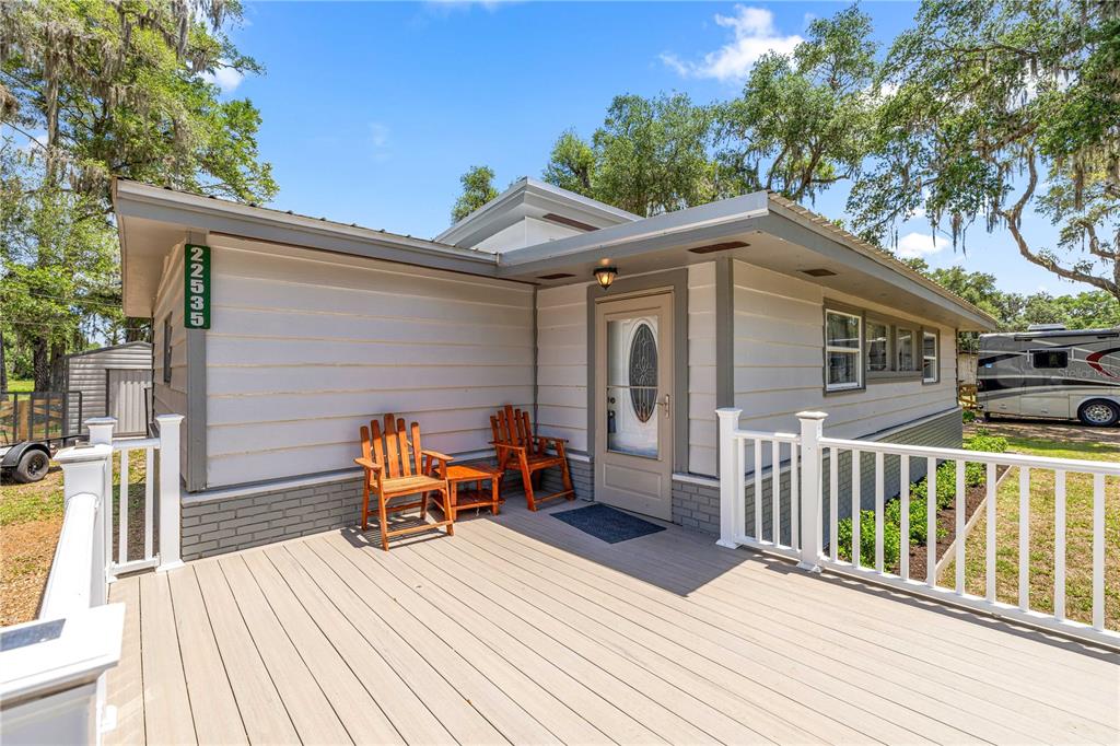 A kitchen features light wood cabinets, dark tile backsplashes, white appliances, and light wood flooring — 22535 SW 117TH STREET, DUNNELLON, FL