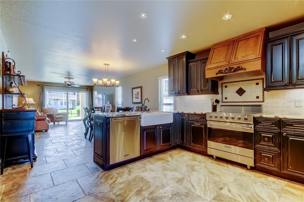 A kitchen with dark wood cabinets, stainless steel appliances, and a farmhouse sink — 7003 SUNSET WAY UNIT 1, ST PETE BEACH, FL