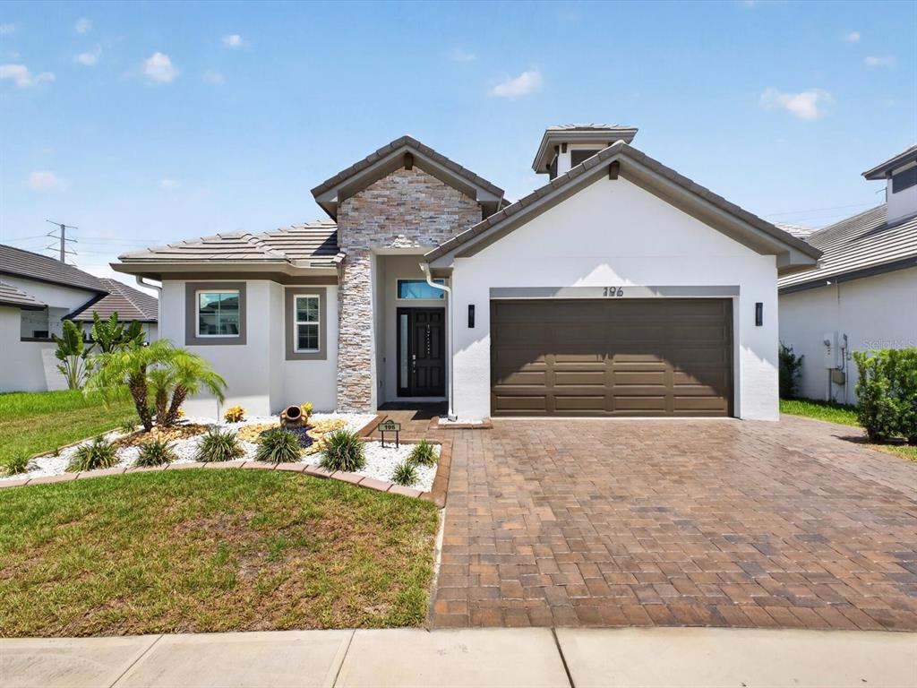 A single-story house with a stone facade, a two-car garage, and a paved driveway — 196 HAMPTON LOOP, DAVENPORT, FL