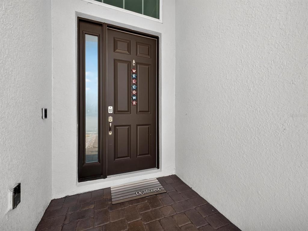A dark brown front door with a side window and a welcome mat — 196 HAMPTON LOOP, DAVENPORT, FL