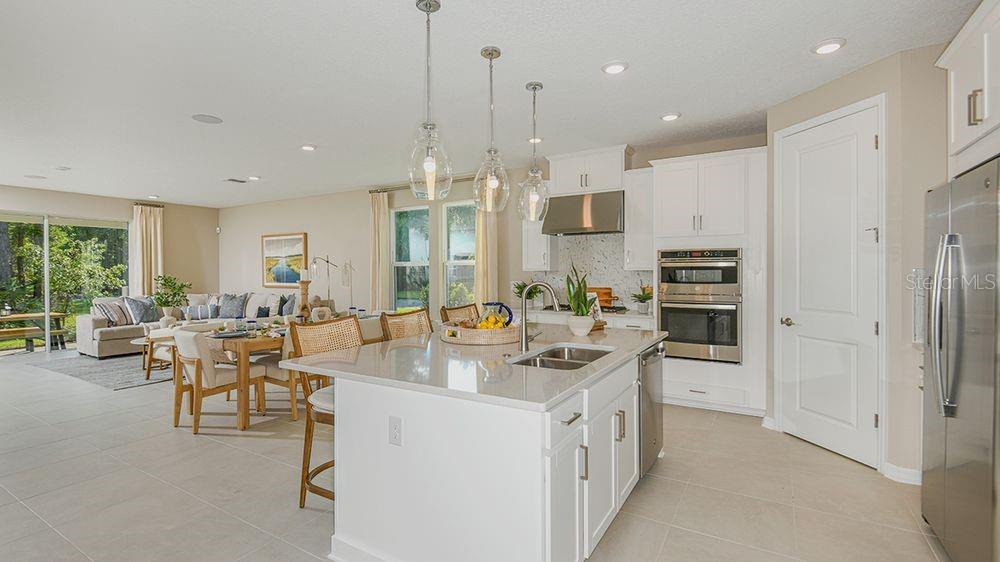 A modern kitchen with a large island, white cabinetry, and stainless steel appliances — 10 ARMENIA COURT, PALM COAST, FL