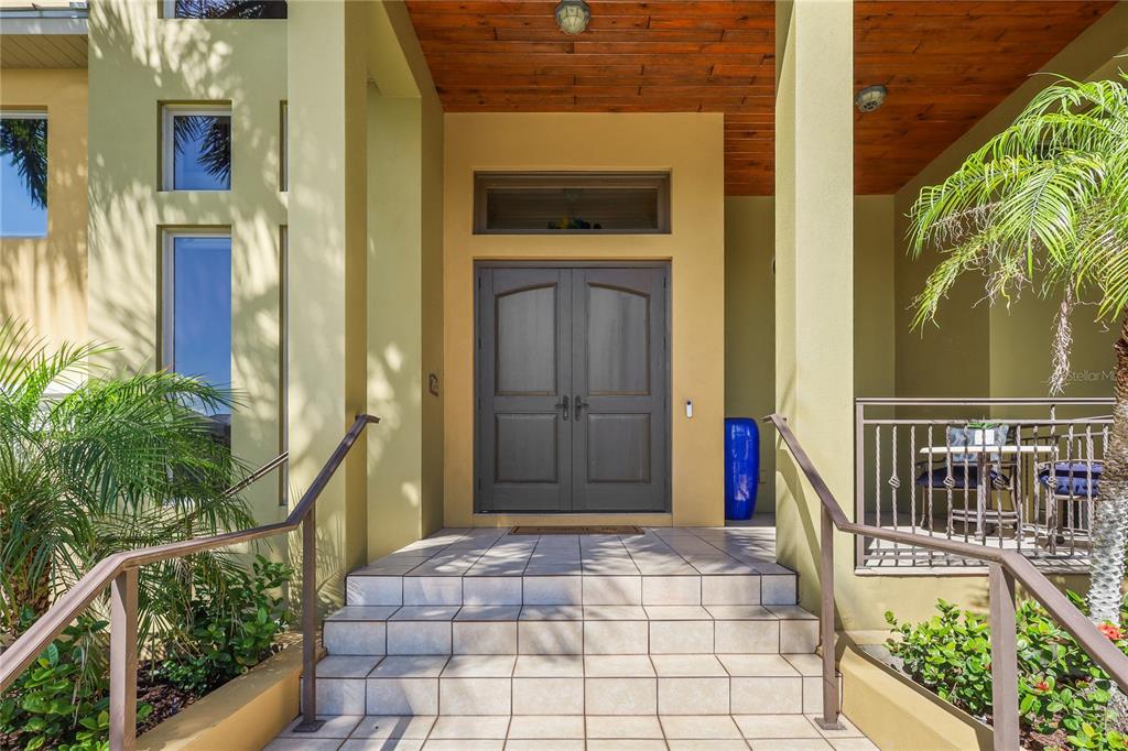 The front entrance features double doors, tiled steps, and a wood-paneled ceiling under a porch — 7158 HAWKS HARBOR CIRCLE, BRADENTON, FL