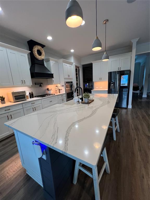 A modern kitchen features white cabinetry, a large marble-patterned island, and black pendant lighting — 6233 RIVO LAKES BOULEVARD, SARASOTA, FL