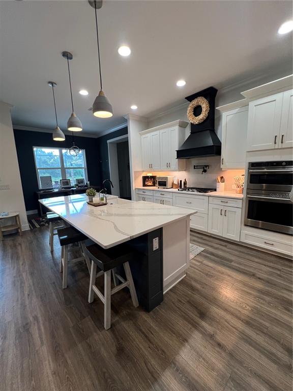 A kitchen features white cabinetry, a large marble-topped island, and a prominent black range hood — 6233 RIVO LAKES BOULEVARD, SARASOTA, FL