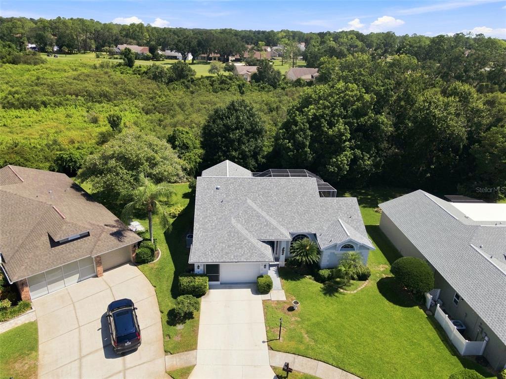 An aerial view shows a suburban house with a gray roof and a screened pool enclosure — 9423 SUMMERBREEZE TERRACE, NEW PORT RICHEY, FL