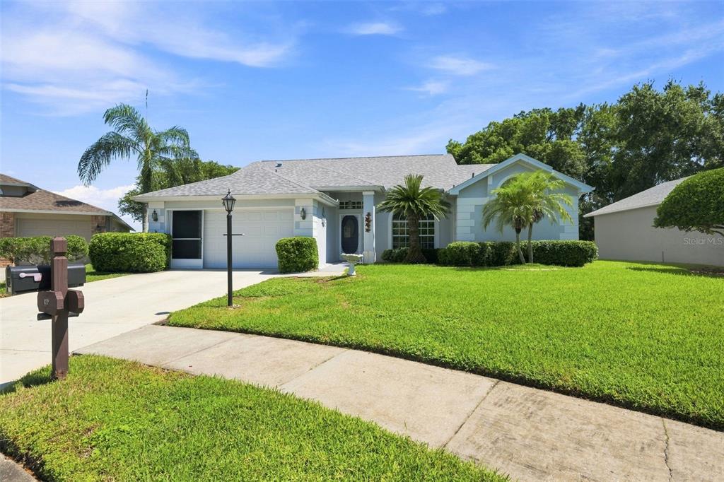 A single-story suburban house with a light-colored exterior, a two-car garage, and a manicured lawn — 9423 SUMMERBREEZE TERRACE, NEW PORT RICHEY, FL