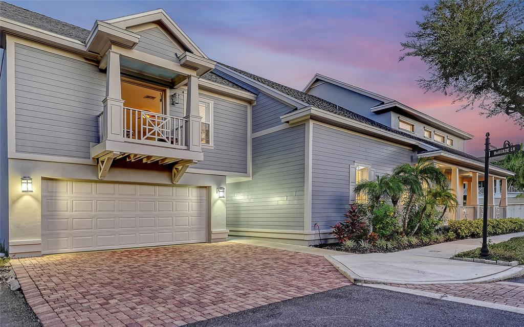A two-story house with blue siding, a brick driveway, and a second-story balcony at dusk — 1775 STAPLETON STREET, SARASOTA, FL