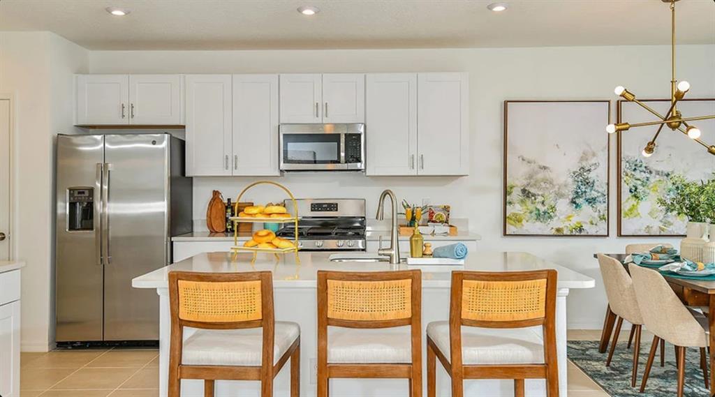 A kitchen features white cabinets, stainless steel appliances, a center island, and three wooden chairs — 13819 SHELLMORE AVENUE, PALMETTO, FL