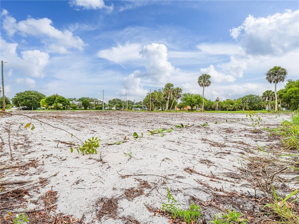 A flat, sandy, cleared vacant lot features scattered debris and several palm trees in the background — 445 OLD DIXIE HIGHWAY, VERO BEACH, FL