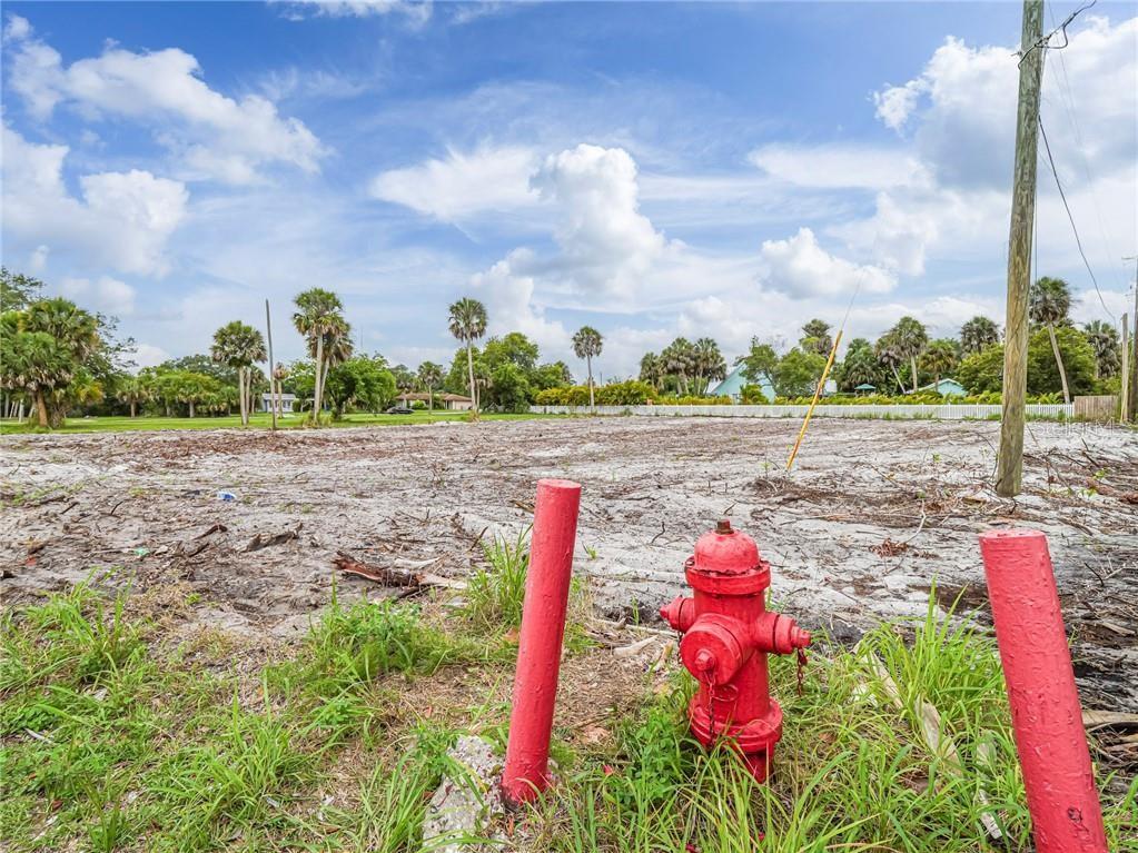 A vacant, cleared lot features a red fire hydrant and two red posts in the foreground — 445 OLD DIXIE HIGHWAY, VERO BEACH, FL