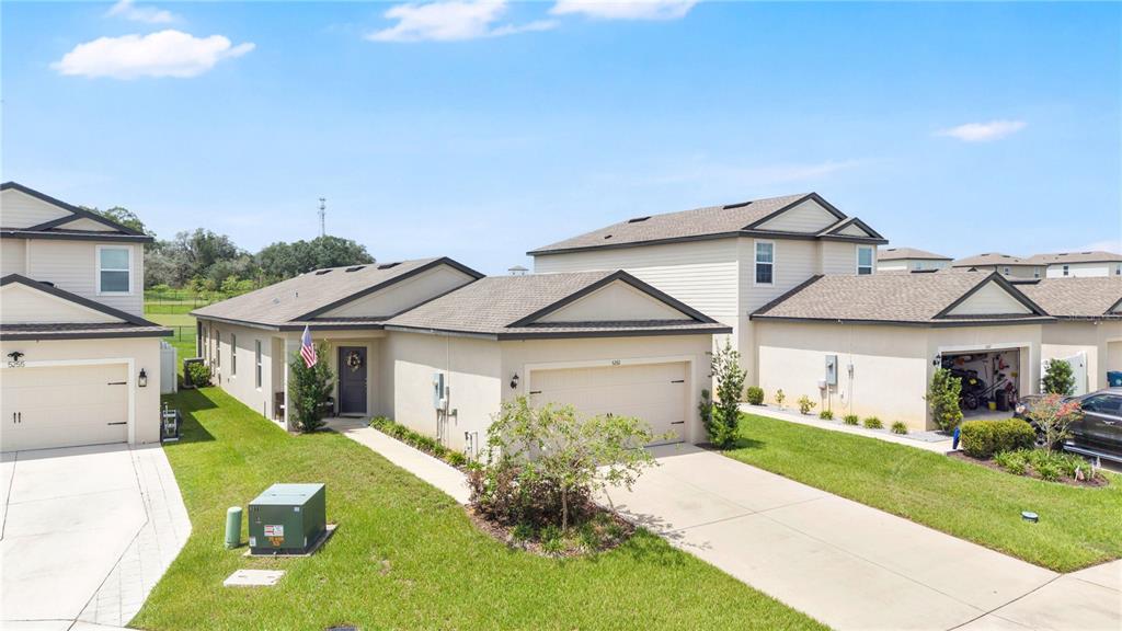 A street-level view of two adjacent suburban houses with beige siding and attached garages — 5261 FEZ COURT, BROOKSVILLE, FL