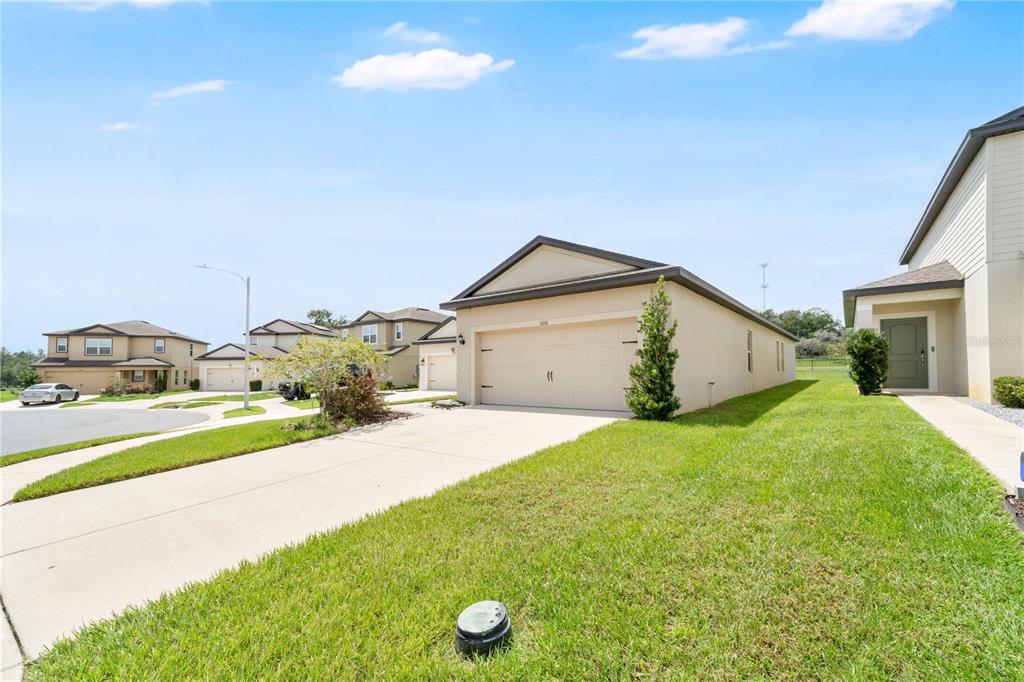 A single-story suburban house with a beige stucco exterior, a two-car garage, and green lawn — 5261 FEZ COURT, BROOKSVILLE, FL