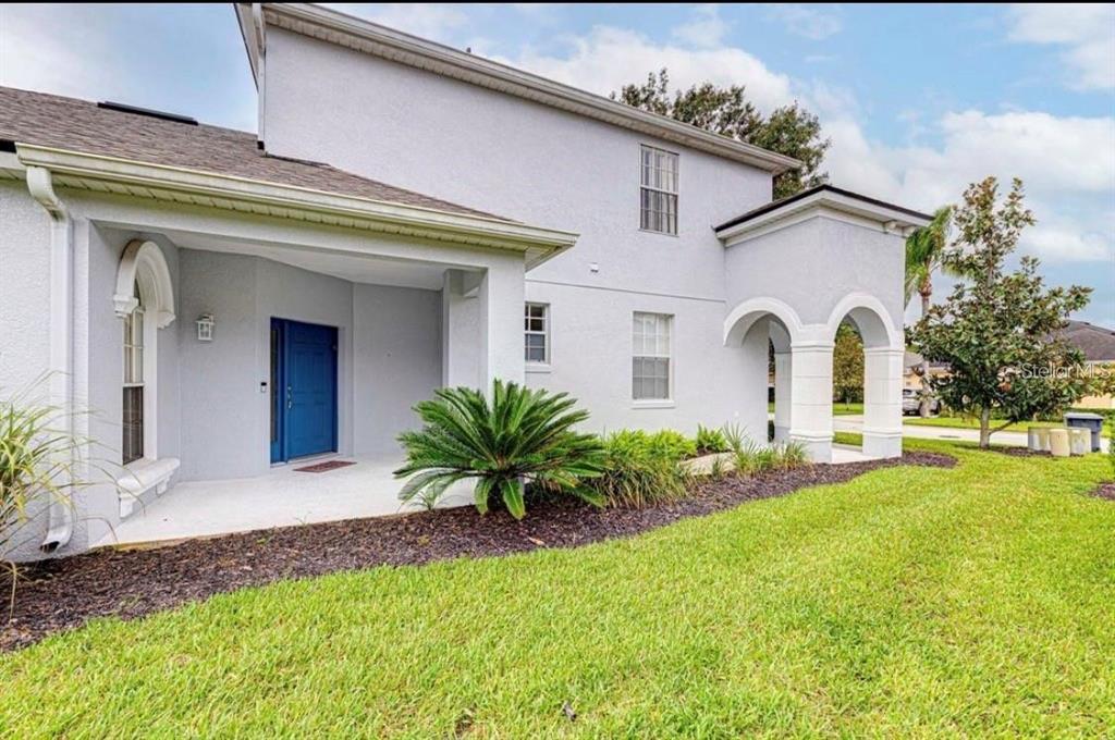 A two-story house with a blue front door, a covered porch, and arched entryway columns — 360 TUPELO CIRCLE, DAVENPORT, FL