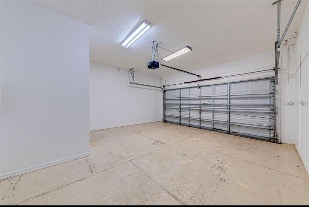 An empty garage with a concrete floor, white block walls, and a metal sectional door — 360 TUPELO CIRCLE, DAVENPORT, FL