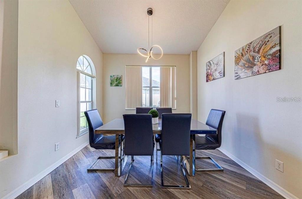 A dining room features a six-chair table, a modern light fixture, and wood-look flooring — 360 TUPELO CIRCLE, DAVENPORT, FL