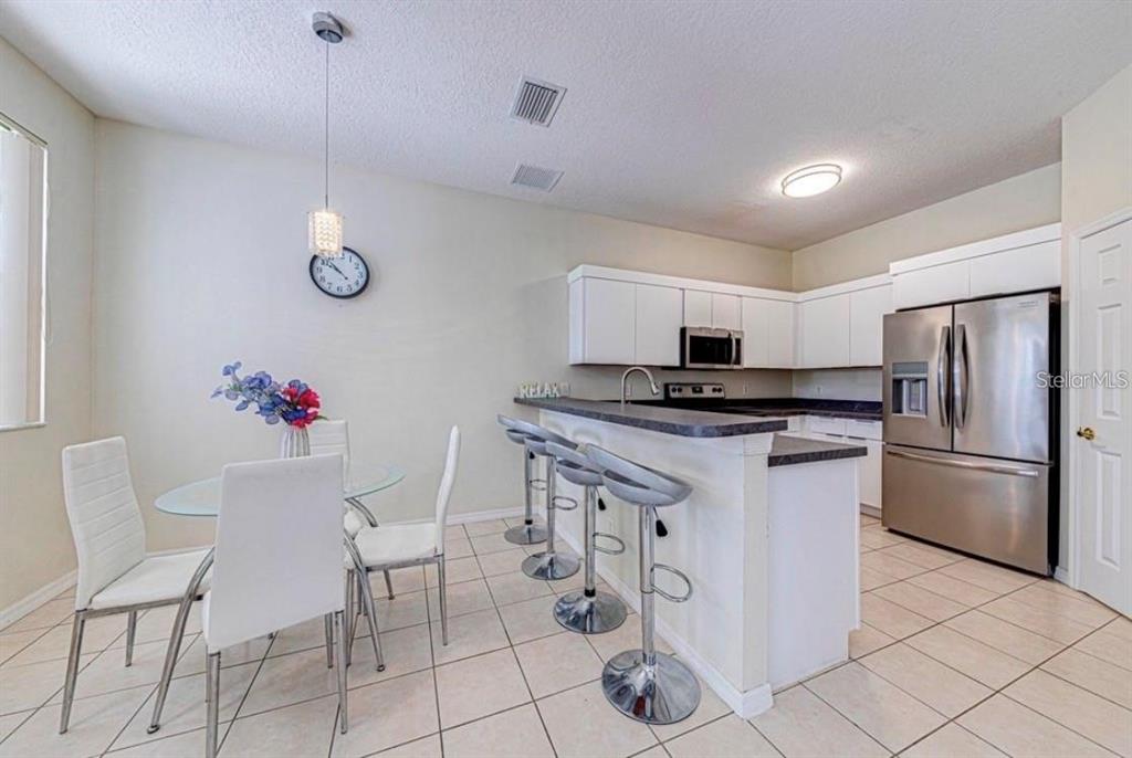 A kitchen with white cabinets, stainless steel appliances, and an adjacent dining area with chairs — 360 TUPELO CIRCLE, DAVENPORT, FL