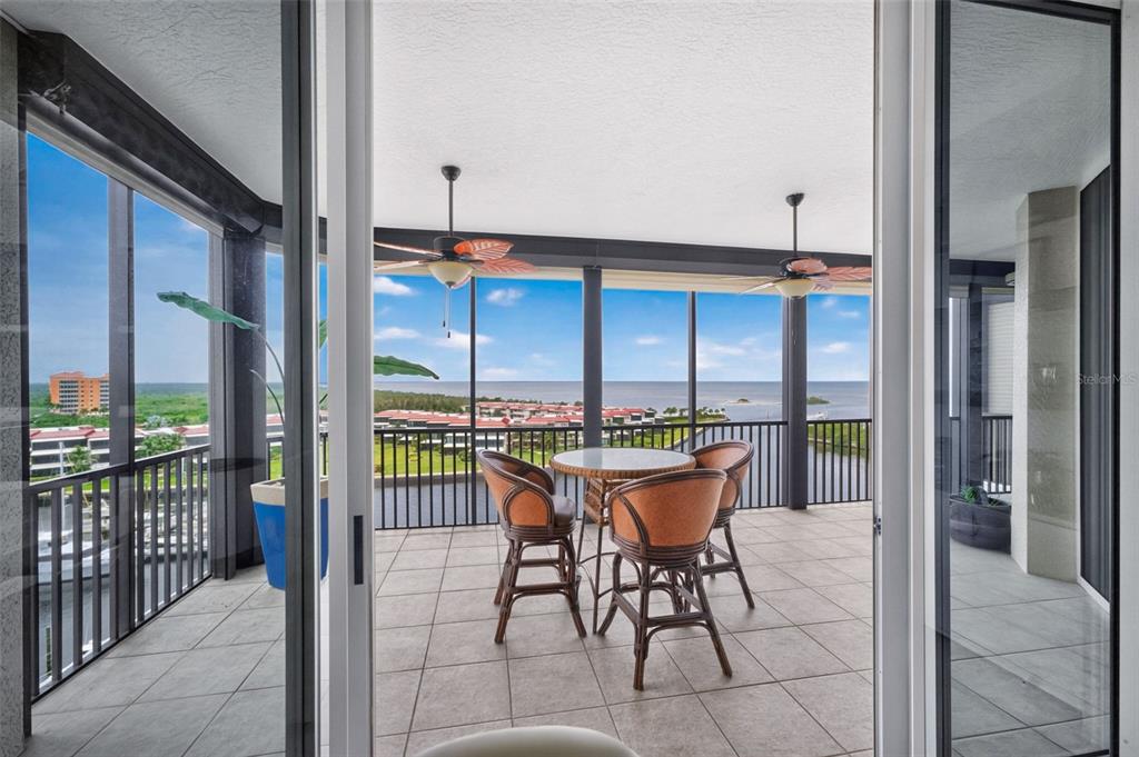 An exterior view of a multi-story white apartment building with palm trees and a parking lot — 3313 SUNSET KEY CIR UNIT 701, PUNTA GORDA, FL