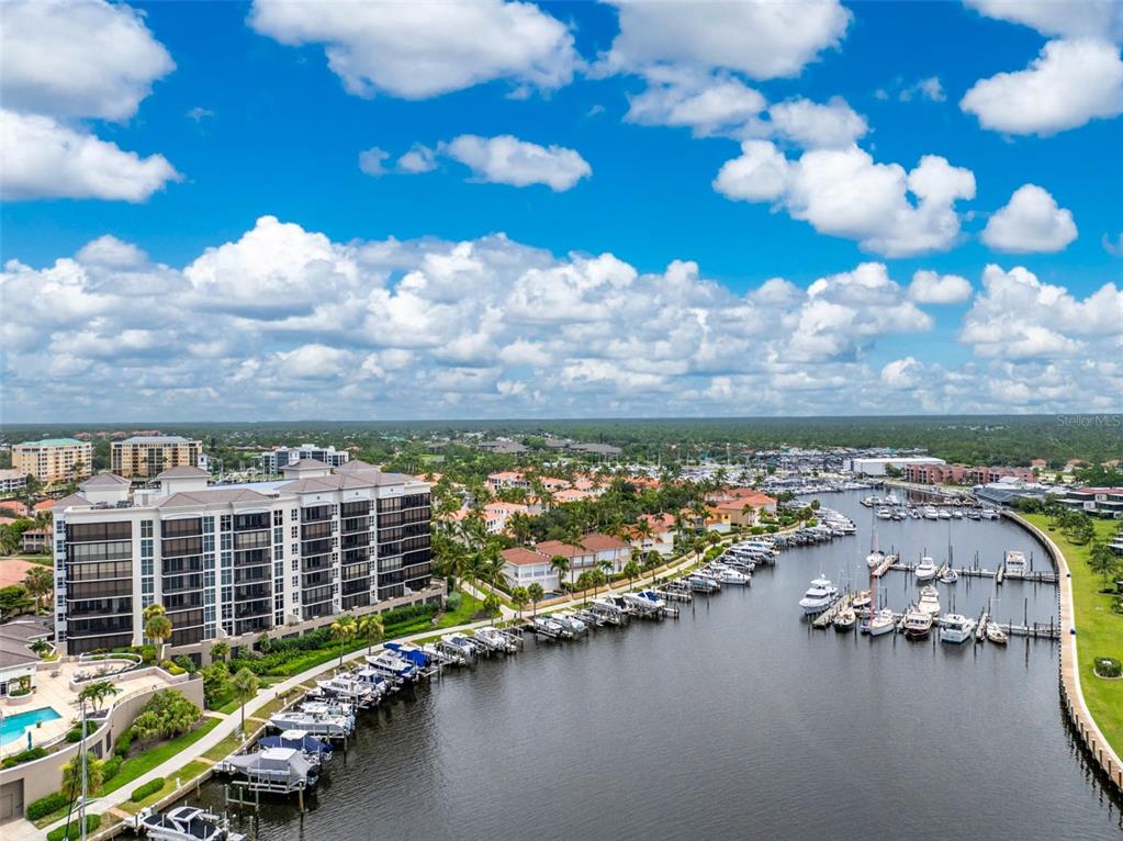 A screened-in balcony features a glass-top table, wicker chairs, two ceiling fans, and water views — 3313 SUNSET KEY CIR UNIT 701, PUNTA GORDA, FL
