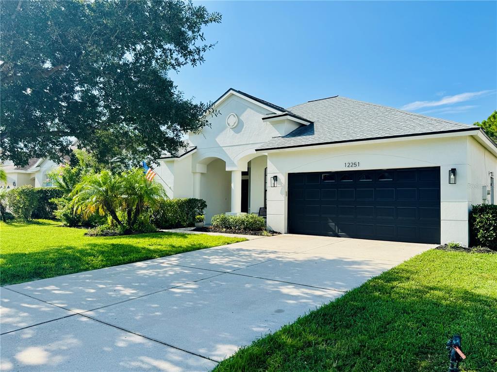 A single-story house with a dark garage door and a concrete driveway at sunset — 12251 23RD STREET E, PARRISH, FL