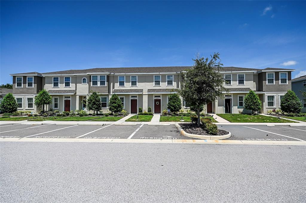 A row of two-story townhomes with a parking lot in the foreground under a blue sky — 6130 FAIRMONT LANE, PALMETTO, FL