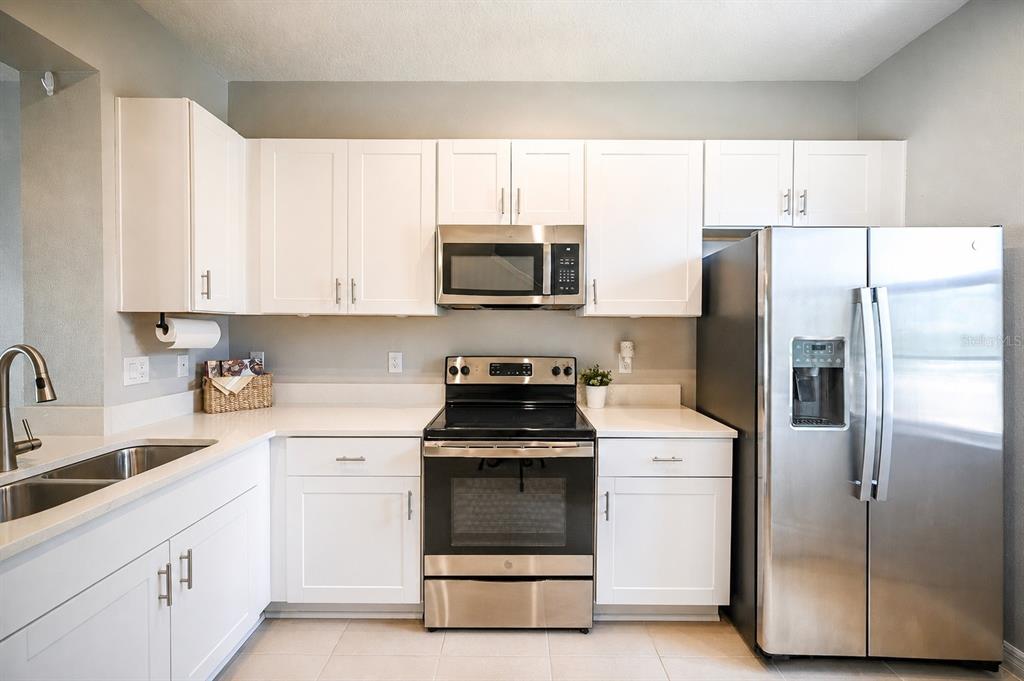 A kitchen features white cabinets, stainless steel appliances, and light-colored countertops — 6130 FAIRMONT LANE, PALMETTO, FL