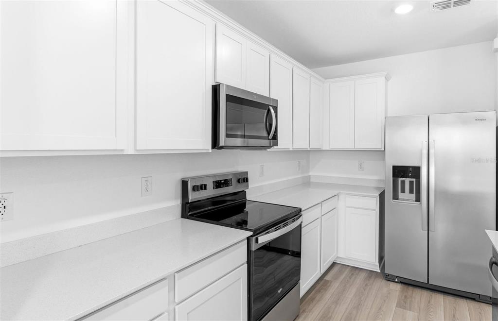 A kitchen features white cabinets, stainless steel appliances, and light-colored countertops — 10422 HIDDEN BANKS GLEN, PARRISH, FL
