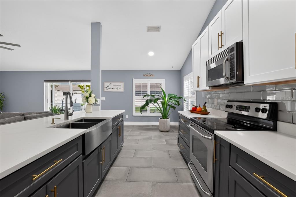 A modern kitchen features dark gray lower cabinets, white upper cabinets, and a stainless steel sink — 17721 HAMPSHIRE OAK DRIVE, TAMPA, FL