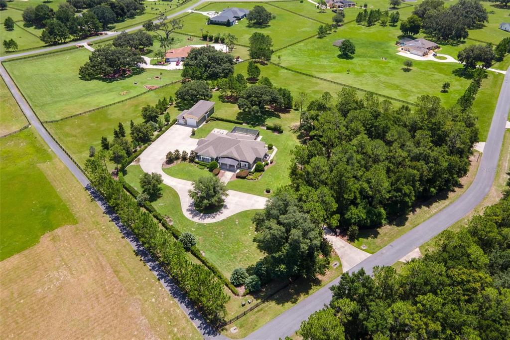 An aerial view shows a house with a pool, detached garage, and surrounding fenced pastures — 10615 NE 104TH CIRCLE, OXFORD, FL