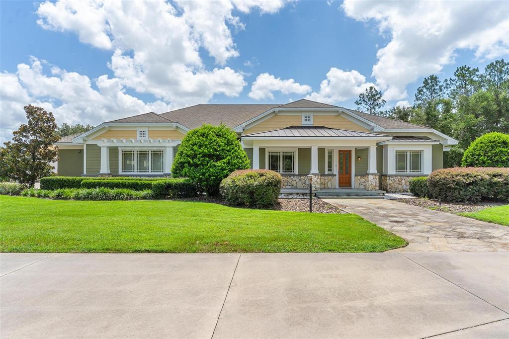 A one-story house with green siding, stone accents, and a stone walkway under a sky — 10615 NE 104TH CIRCLE, OXFORD, FL