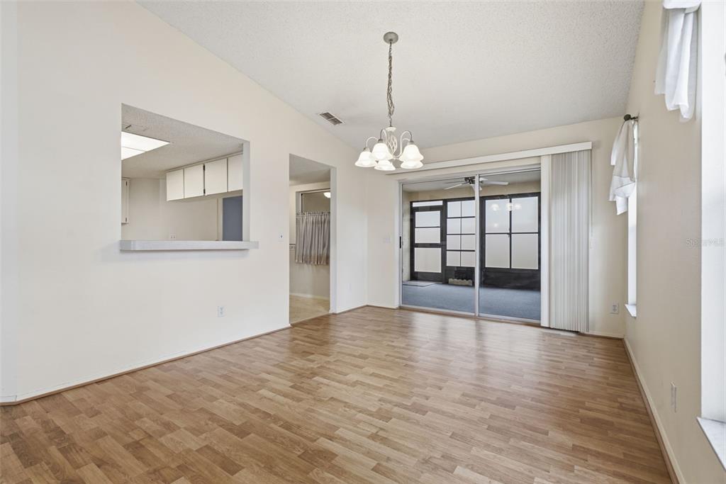 An empty living room with wood-look flooring, light-colored walls, a ceiling fan, and blue curtains — 3960 SAILMAKER LANE, HOLIDAY, FL