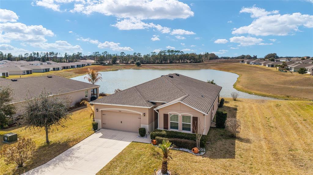 An aerial view of a single-story suburban house with a garage next to a pond — 9238 SW 60TH TERRACE ROAD, OCALA, FL