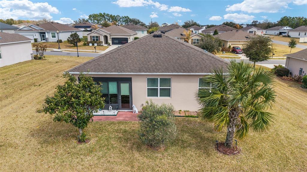 The rear exterior of a single-story house features a screened patio, lawn, and palm tree — 9238 SW 60TH TERRACE ROAD, OCALA, FL
