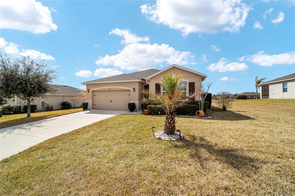 A single-story house with a beige exterior, a two-car garage, and a front yard palm tree — 9238 SW 60TH TERRACE ROAD, OCALA, FL