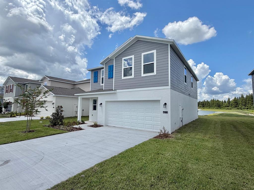 A two-story house features a white stucco lower level, gray siding, and a two-car garage — 6213 BOTTICELLA BOULEVARD, WINTER HAVEN, FL