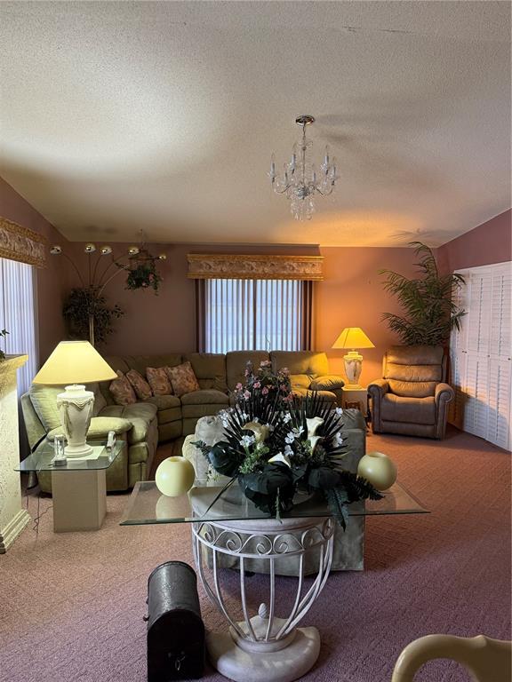 A living room features a sectional sofa, a glass-topped pedestal table, and mauve carpeting — 7309 ELEANOR CIRCLE UNIT 7309, SARASOTA, FL