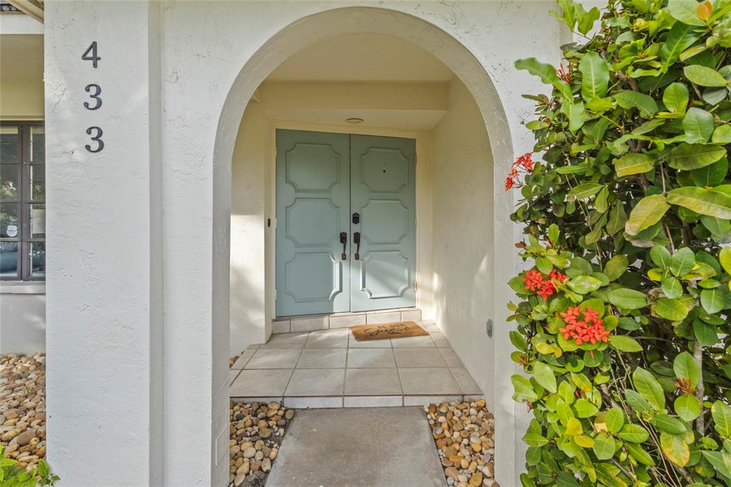 A light blue double door with decorative molding sits under an arched entryway — 433 WHITFIELD AVENUE, SARASOTA, FL