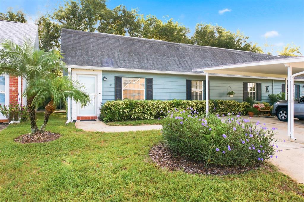 A light blue single-story house features a front door, a carport, and a landscaped yard — 6206 WILDS DRIVE UNIT 5A, NEW PORT RICHEY, FL