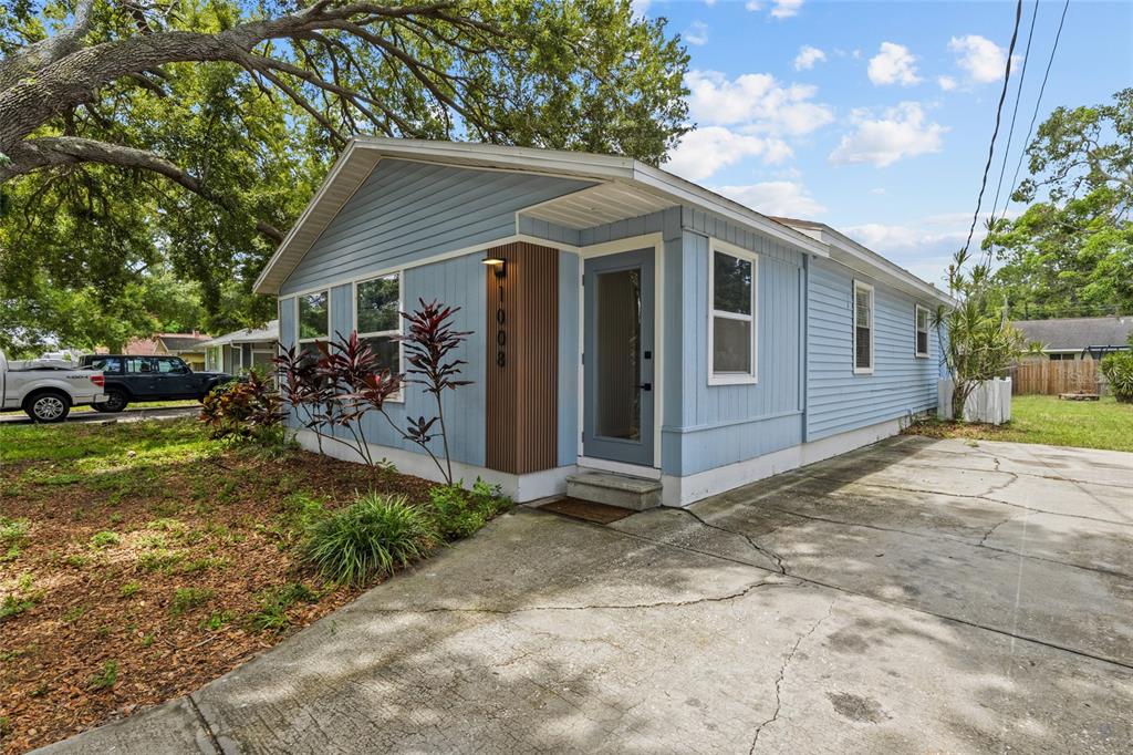 A light blue house with vertical wood slats and a concrete driveway under large trees — 1008 37TH STREET W, BRADENTON, FL