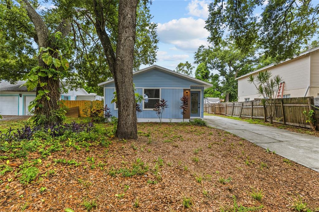 A light blue single-story house with a concrete driveway and large trees in the yard — 1008 37TH STREET W, BRADENTON, FL