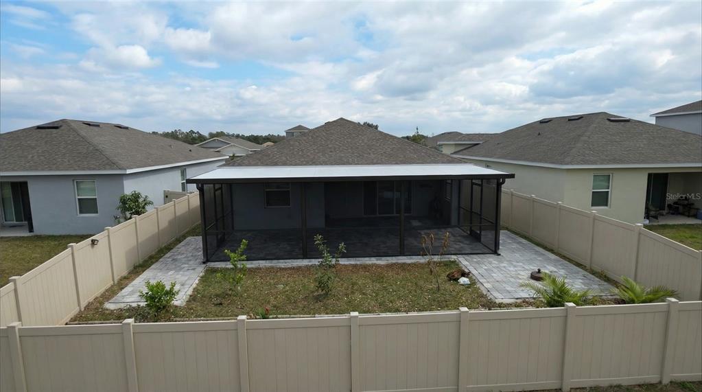 An aerial view of a backyard featuring a screened-in patio and a vinyl privacy fence — 693 CROWN ROSE DRIVE, EAGLE LAKE, FL